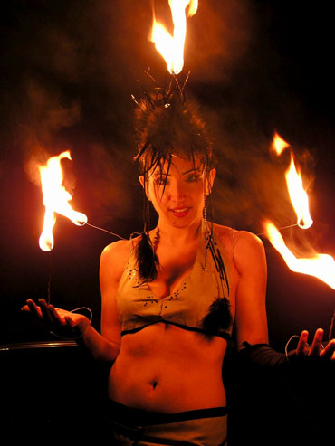 Une professionnelle porte sur son costume de scene des torches en feu  pour demarrer son numero flamboyant