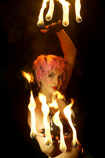 Une artiste manipule le feu avec des gants prevus pour supporter des tiges enflammees au bout des doigts