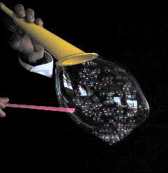 Des minus bulles de savon sont formees dans une bulle ovale a l'aide de deux accessoires