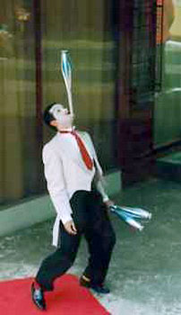 Ce jongleur mime maintient une massue sur son menton pour animer l'entree d'un restaurant