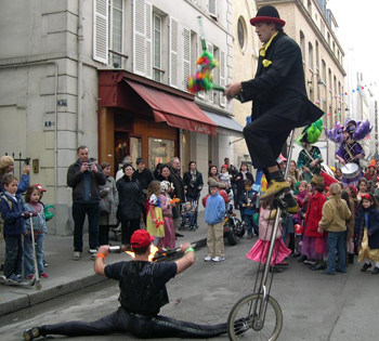 Un clown jongle sur son monocycle tandis qu'un acrobate effectue un grand ecart au sol