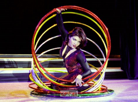 Une professionnelle de hula hoop termine son show accroupie dans ses cerceaux muticolores