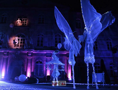 Les echassiers des Jouets de Noel en parade lumineuse de blanc une nuit de fete de ville