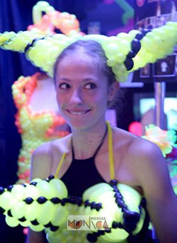 Une jeune ballooneuse porte sa creation de mode design composee d un corset pointu et d un bicorne en ballons jaunes et noirs