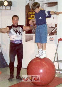 Un athlete du cirque initie un enfant a l'equilibrisme sur un ballon geant