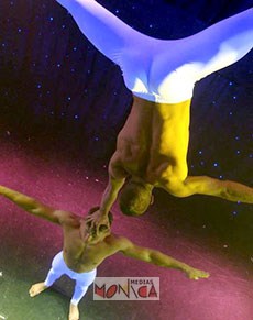 Duo d'acrobates realisant un numero de porté :  le voltigeur se maintient en equilibre au bout de son bras tendu posé au dessus de la tete du porteur