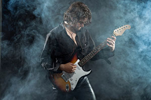 Un artiste de rock psychedelique joue sur sa guitare dans la fumee sur scene