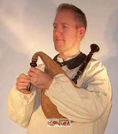 Musicien breton jouant du biniou petite cornemuse avec poche a air maintenue sous le coude