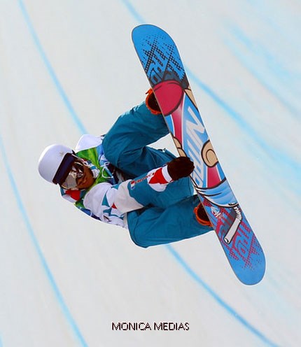 Un snowboarder en plein elan saisit le board d'une main entre les deux pieds