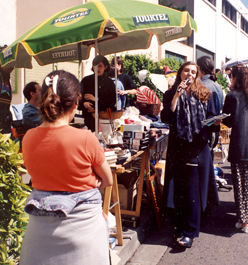 Une animatrice donne de la vie a un vide grenier avec son micro aupres du stand d'un particulier