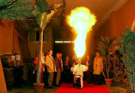 Un artiste fakir agenouille sur un tapis rouge crache du feu pour une animation a l'interieur