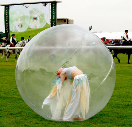 Une danseuse en bulle se contorsione sur l'herbe d'un hippodrome