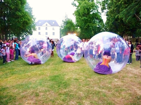 Trois danseuses en bulles sur l'herbe font une animation dans un parc