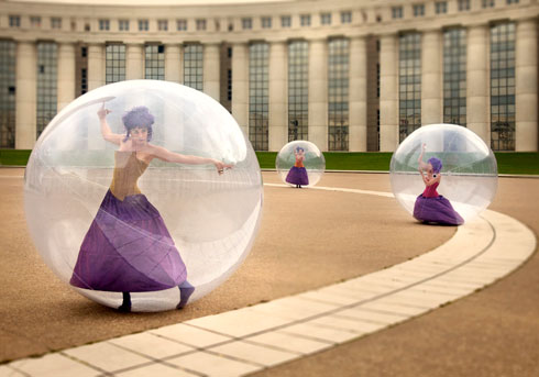 Trois danseuses en bulles sont a l'exterieur sur une grande place de la ville