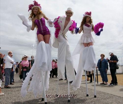 Trois echassiers cabaret belle epoque dans la foule face a la mer