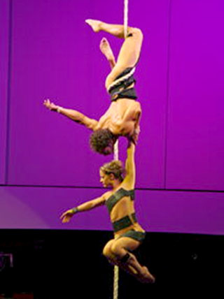 La danseuse tient dans les airs par la force du bras de son partenaire qui est enroule a la corde lisse