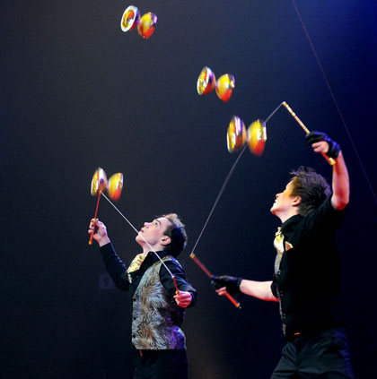 Ces deux jongleurs lancent simultanement en l'air leurs diabolas pour realiser une figure tres aerienne