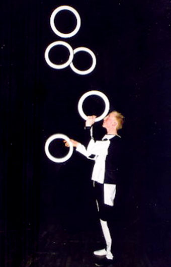 Nicolas lance une serie d'anneaux en l'air et jongle au rythme de la musique du cirque