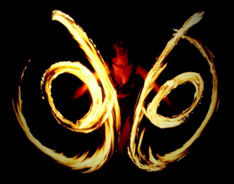 Une femme feu effectue simultanement deux spirales enflammees lors d'un show pyrotechnique