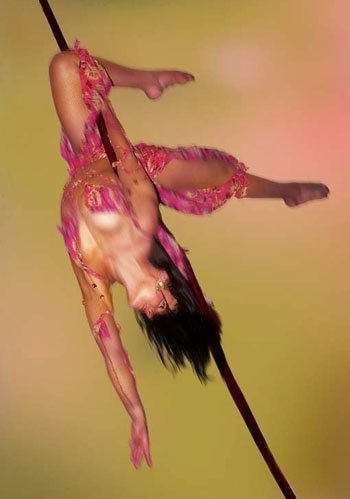 Une danseuse realise une choregraphie aerienne la tete en bas sur une corde lisse pour un spectacle tres visuel