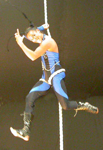 La danseuse se tient d'un seul bras a la corde lisse et danse en hauteur sur la musique du spectacle