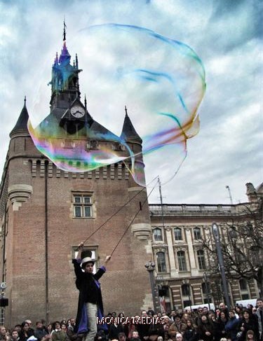 Le magicien laisse echapper une bulle geante face a l'horloge de la mairie