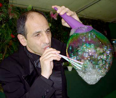 Un artiste fait apparaitre plusieurs petites bulles de savon dans une plus grosse bulle pour un moment tres magique