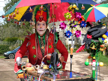 L'artiste mime et clown aux commandes de son triporteur musical sous son parapluie magique