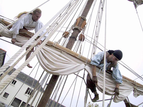 Deux hommes de l'equipage hissent les voiles du bateau