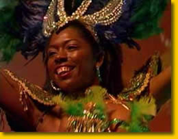 Une danseuse bresilienne porte un costume en plumes vertes et une grande coiffe doree