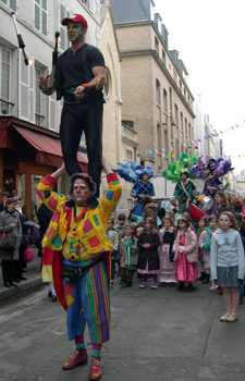 Un artiste acrobate jongle sur les epaules d'un clown lors d'une deambulation de rue