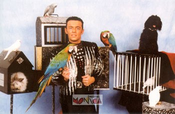 Ce specialiste du cirque avec son costume noir et argente tient un tient un perroquet sur sa main droite