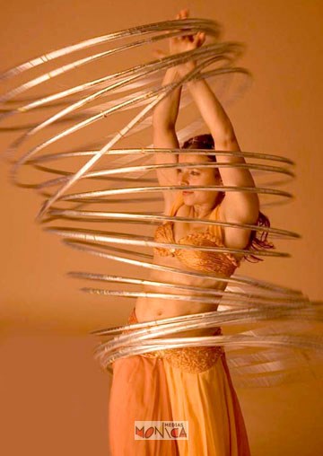 Cette danseuse orientale fait tourner un grand nombre de cerceaux autour de sa taille avec beaucoup de technique