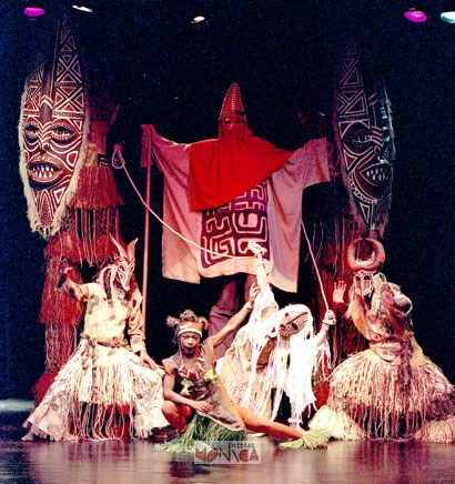 Les echassiers de l'afrique avec leurs grands masques sont entoures de musiciens et danseurs sur scene
