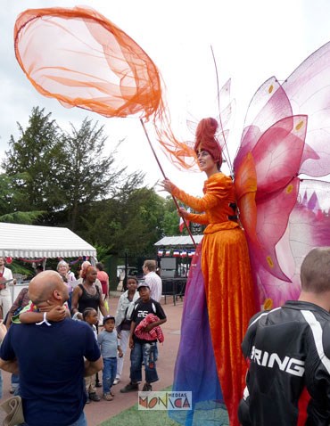 Madame papillon sur echasses chassant des invtes dans une fete avec son filet