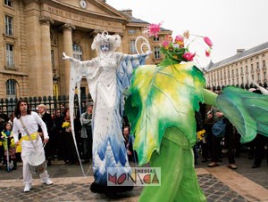 Une blanche reine des neiges sur echasses ouvre les bras pour accueillir un lutin vert feuille