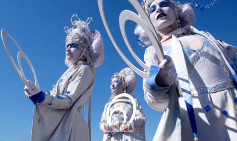 Trois blanches echassieres reines des neiges sont tournees vers le public pendant leur parade musicale de Noel par un beau ciel bleu