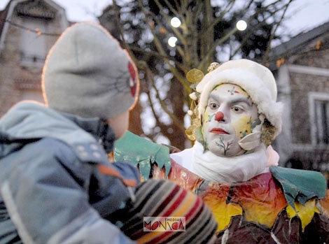 Un lutin maquille aux couleurs des fetes de noel regarde un enfant droit dans les yeux