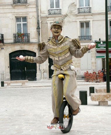 Cet artiste du cirque tient une boule de jonglage dans chaque main assis sur un monocycle