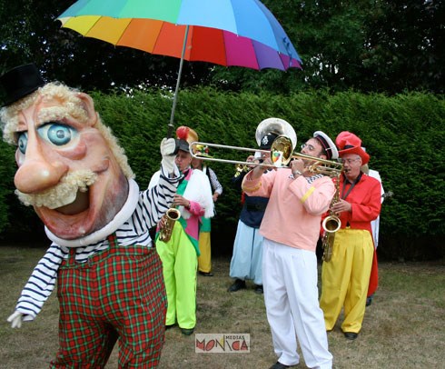 Un enorme toon souriant tient un parapluie pres de l'orchestre festif