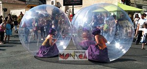 Des comediennes enfermées dans des bulles geantes roulent sur le sol lors d'un spectacle de rue