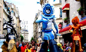 Troupe de sorciers indiens geants vivement colores deambulant parmi la foule un ete dans les rues de Paris