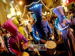 Groupe de percussionistes lumineux avec tambours defilant dans une rue lors d'une fete de ville nocturne