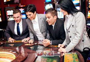 Joueurs autour d'une table de roulette lors d une soiree casino devant des machines a sous