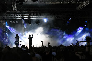 Un concert rock de musique new wave avec sur scène le chanteur entrainant le public pres de son guitariste