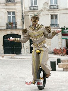 Jongleur de rue en costume sur monocycle