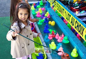 Une petite fille avec une canne joue a la peche aux canards lors d une kermesse pour enfants