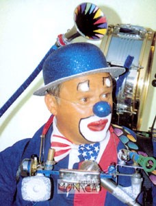 L homme orchestre est maquille avec un nez bleu clownesque