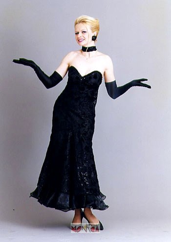Chanteuse interprete des grands tubes francais vetue d une robe fourreau avec de grands gants, écharpe et escarpins noirs.