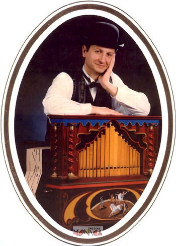 L organiste habille en noir et blanc est accoude sur son orgue de barbarie